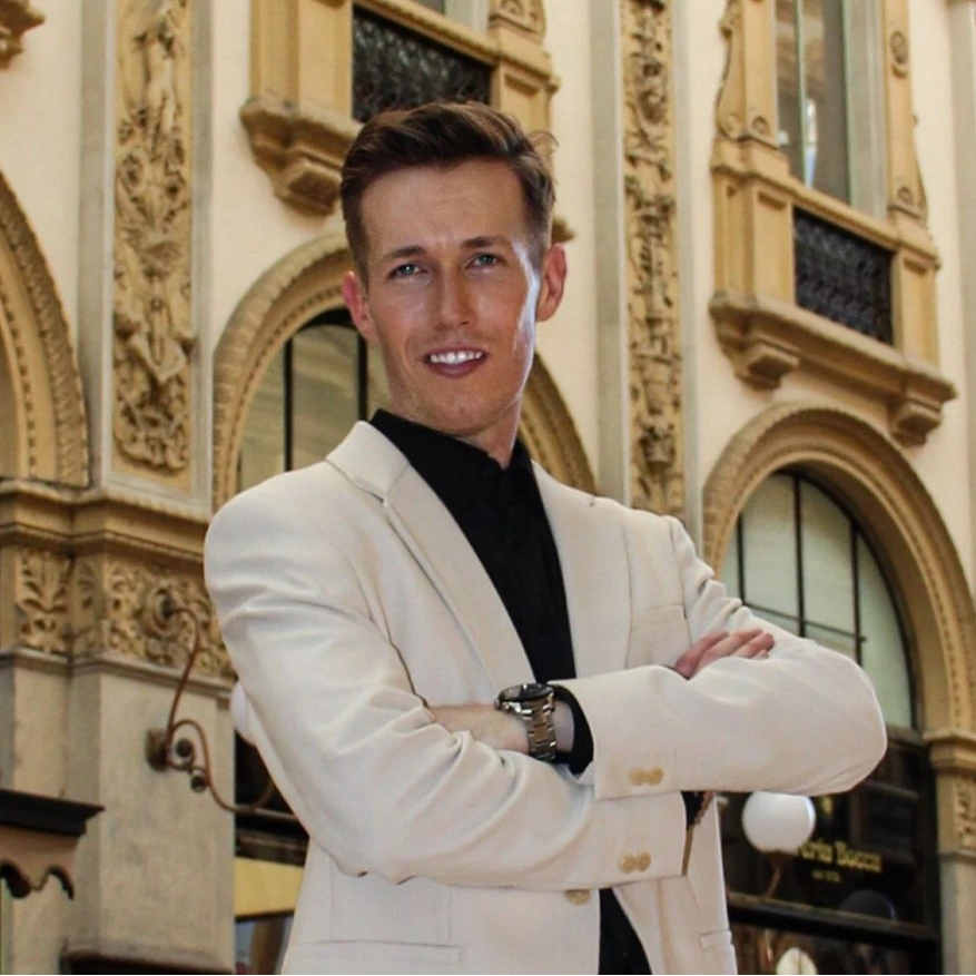 Portrait of a man in a light suit standing before an ornate building