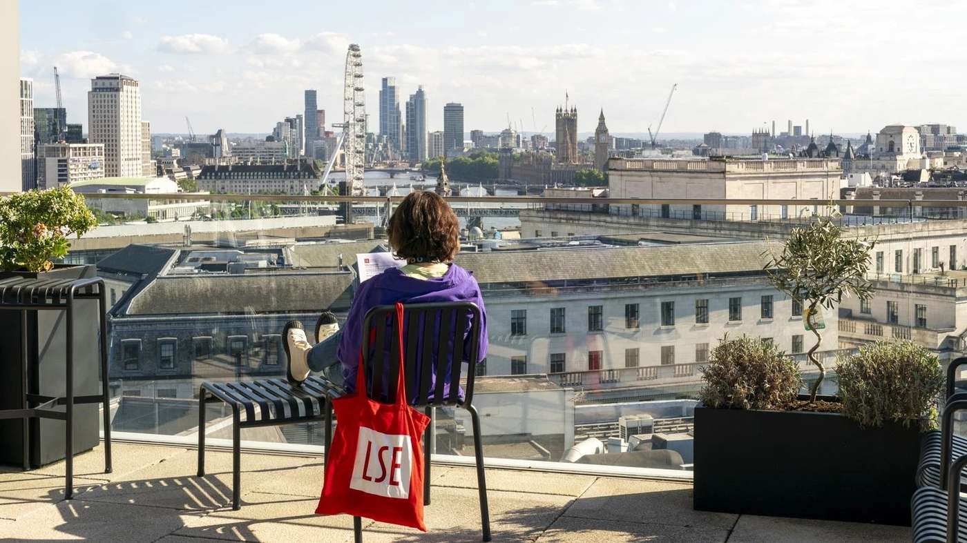 Student seated on an LSE rooftop terrace overlooking the London skyline.