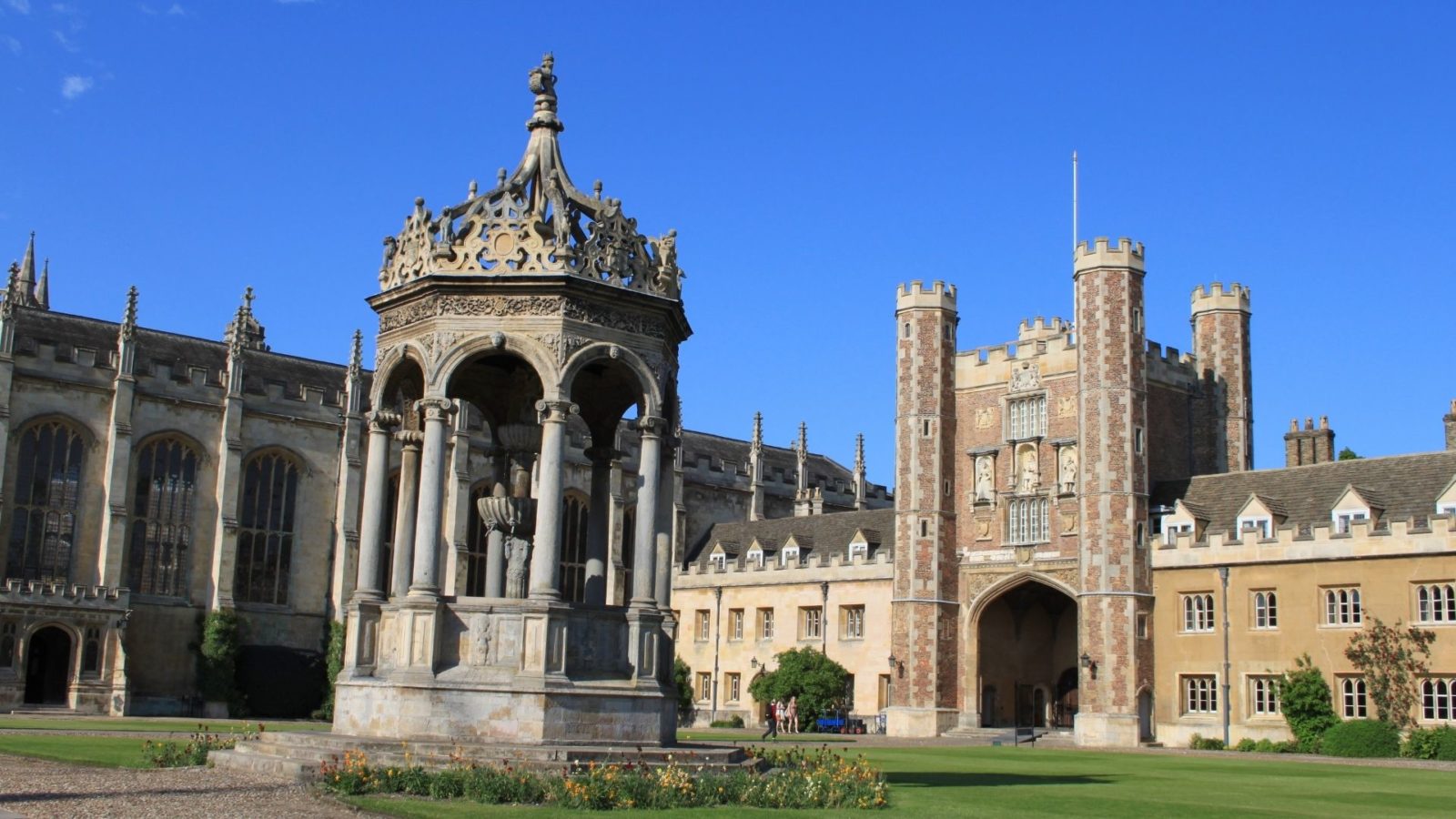 Historic Trinity College Cambridge buildings and lawn under a blue sky