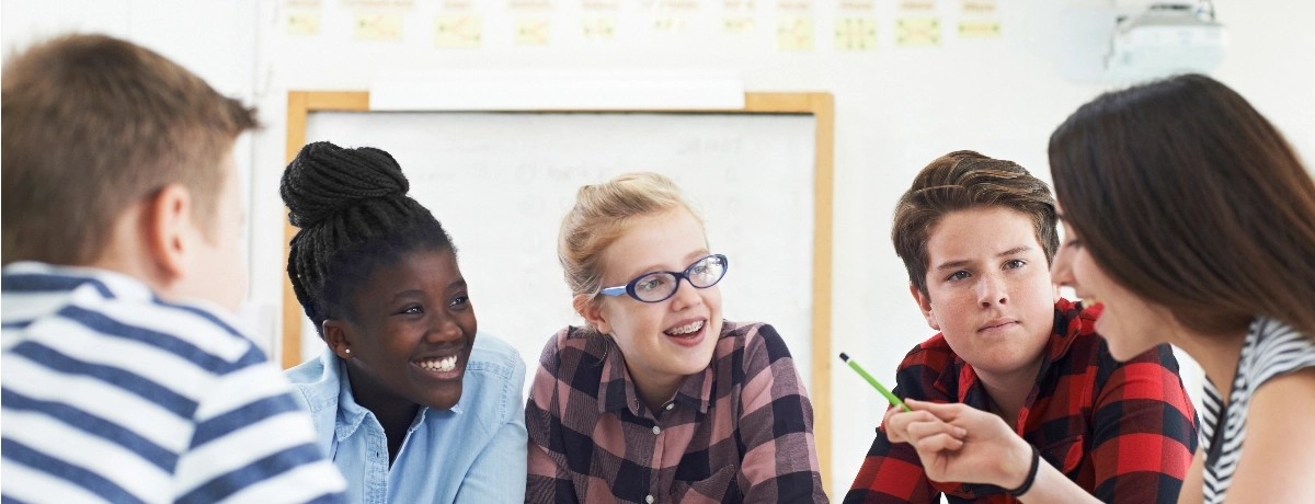 Five students collaborating and talking in a classroom