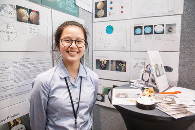 Student smiling beside her project display at a TeenTech event